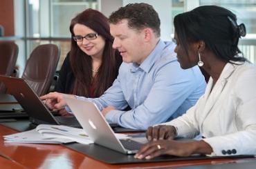 Employees smile as they review data on a laptop